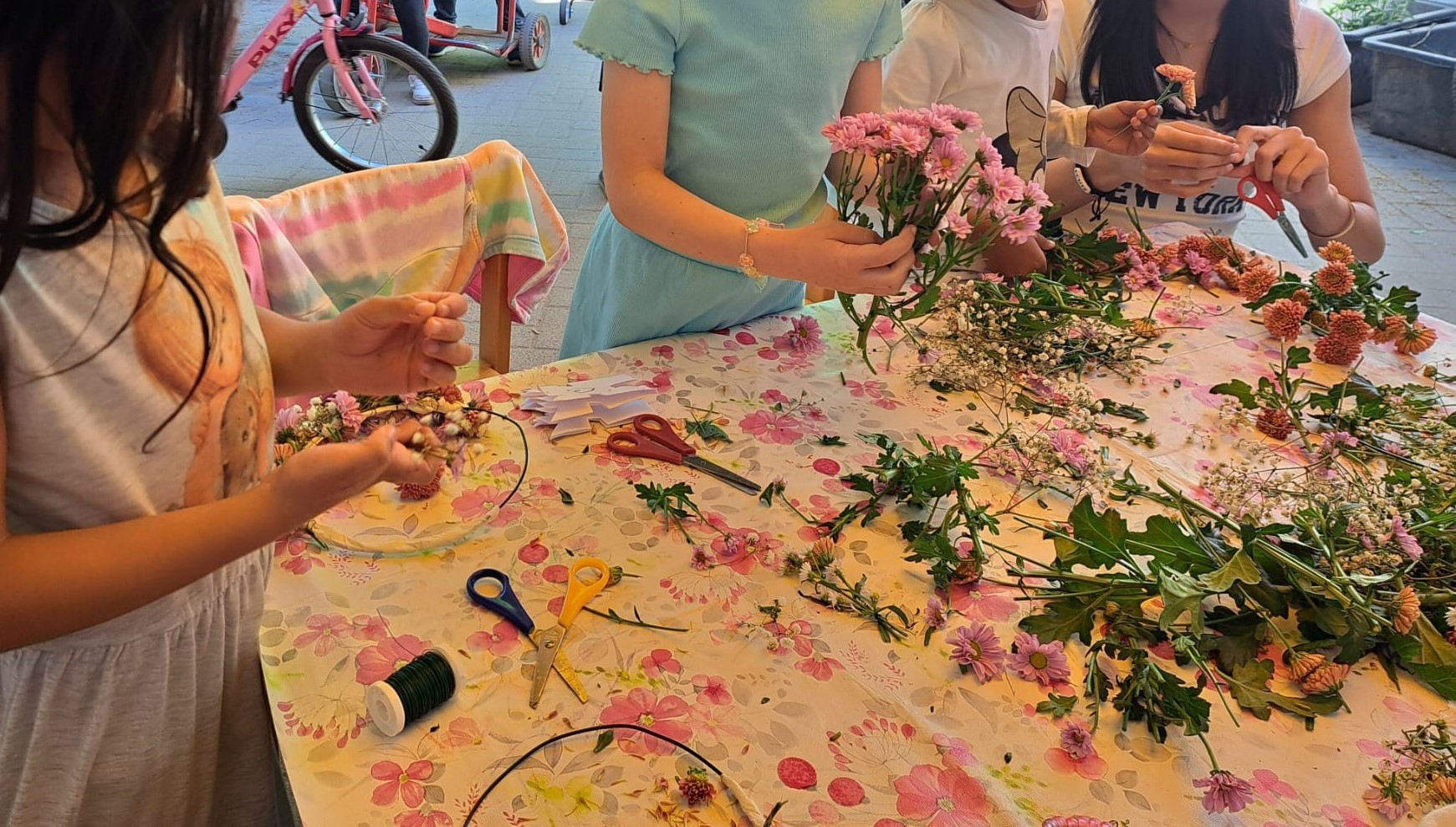Kinderhände beim Blumenkranzflechten