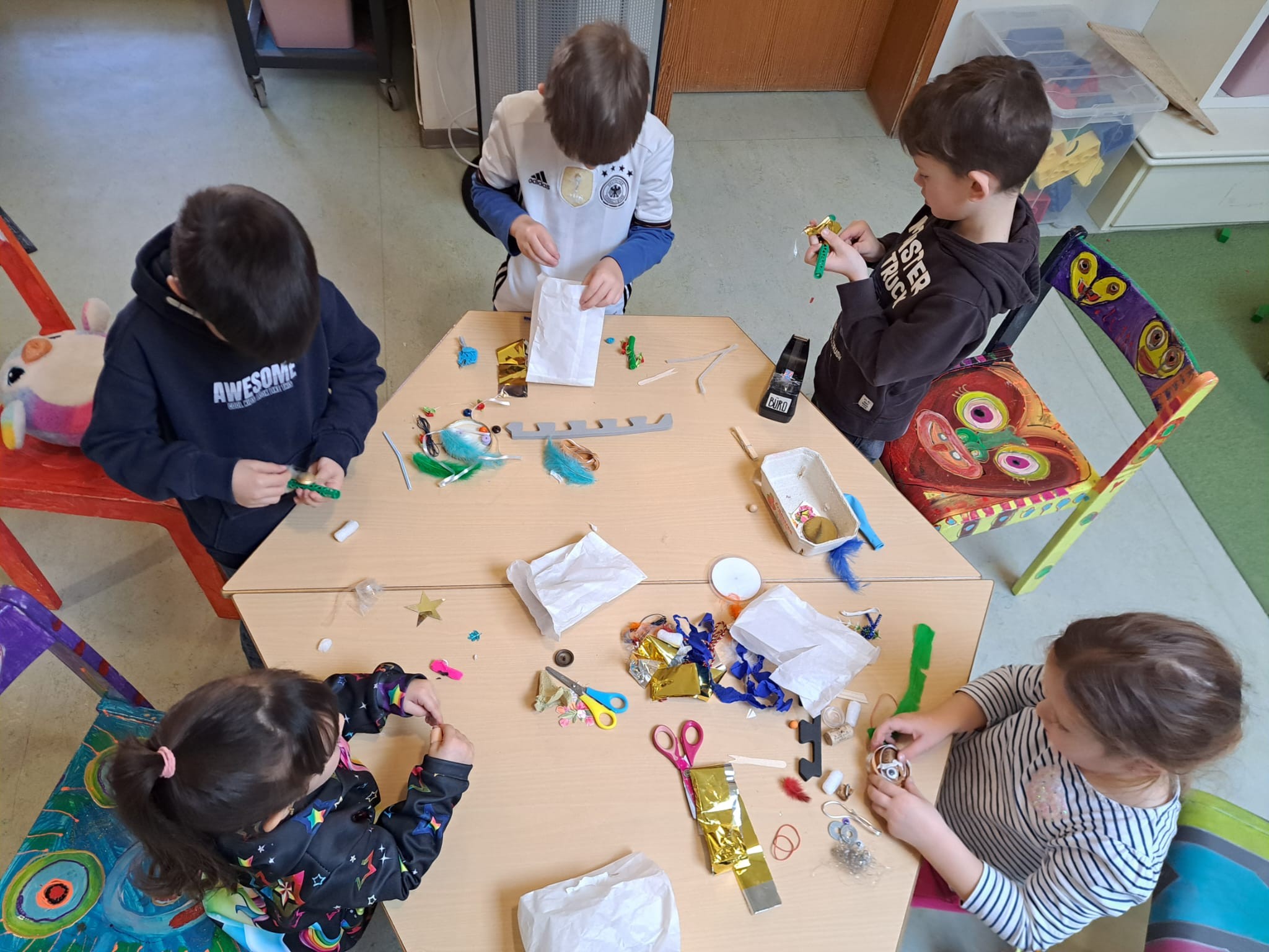 Kinder mit vielen Bastelmaterialen an einem Tisch.